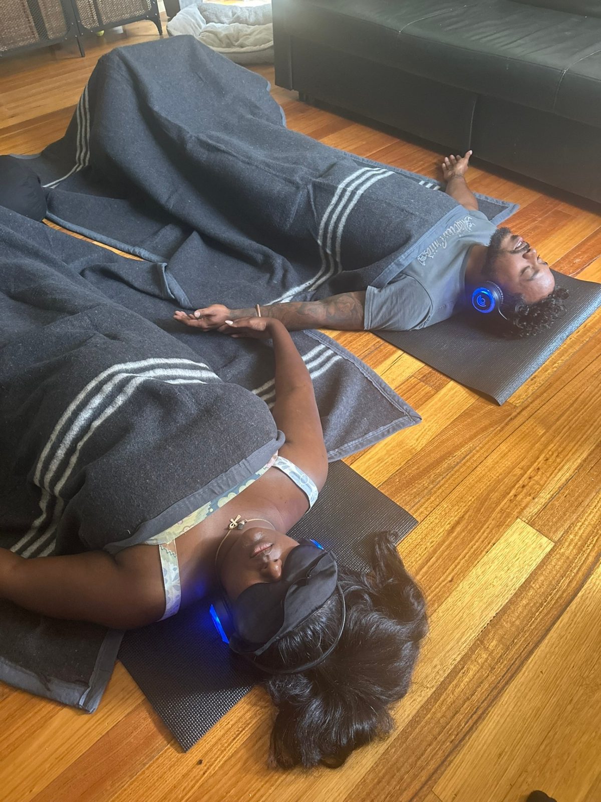 Two clients resting side by side wearing 9D Breathwork headphones in a semi-private session