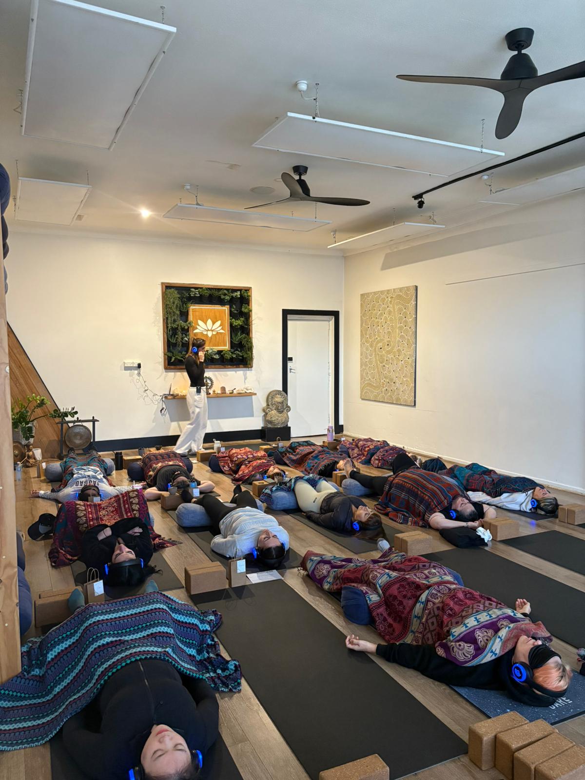 Group 9D Breathwork session at Breath Vortex Melbourne — participants resting on mats with LED headphones
